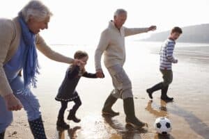 estate planning lawyer Anaheim, CA with grandparents playing soccer on the beach with their grandkids