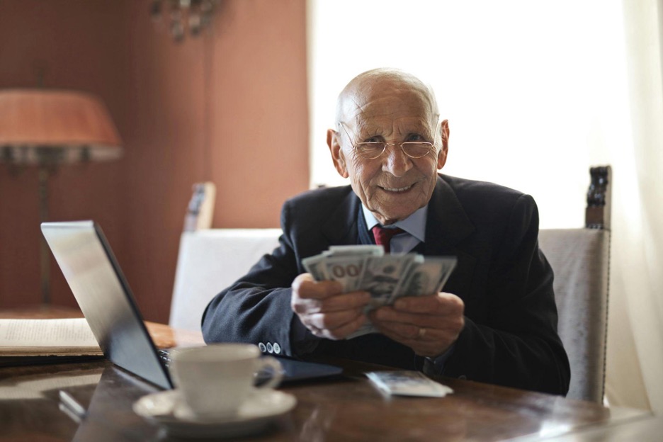 An image from Pexels, showing an elderly man wih a handful of cash after speaking with an estate planning lawyer Orange, CA